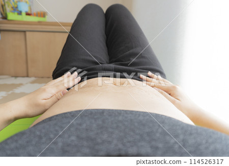 一位女士仰躺在瑜珈墊上,腹部有產後妊娠紋 一位女士仰躺在瑜珈墊上,腹部有產後妊娠紋 114526317