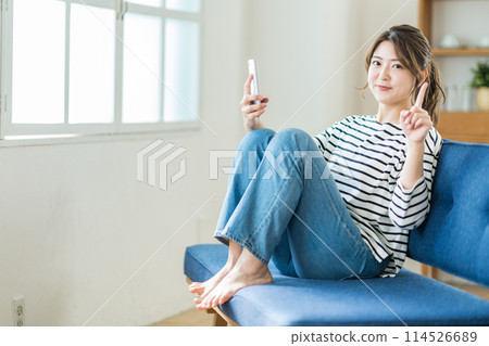 在客廳裡操作智能手機的年輕女子。 114526689