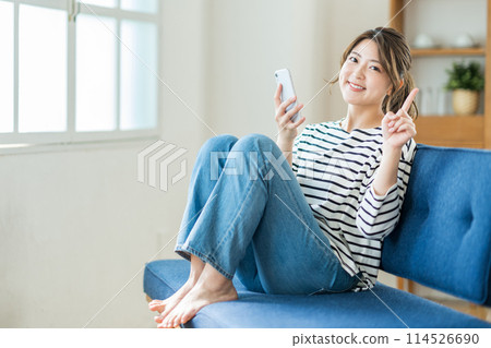 在客廳裡操作智能手機的年輕女子。 114526690