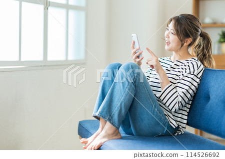 在客廳裡操作智能手機的年輕女子。 114526692