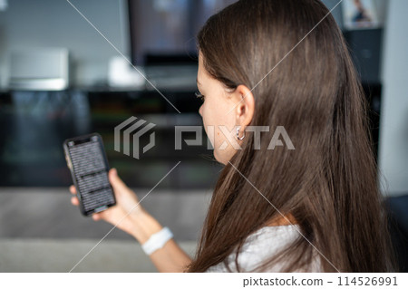 Young woman reads a online book on her smartphone 114526991