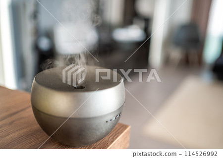 Grey aroma oil diffuser on light table at home, space for text. Air freshener 114526992