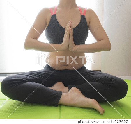 肚子上有產後妊娠紋的女士,盤腿坐在瑜珈墊上,雙手合十擺出瑜珈姿勢。 肚子上有產後妊娠紋的女士,盤腿坐在瑜珈墊上,雙手合十擺出瑜珈姿勢。 114527007