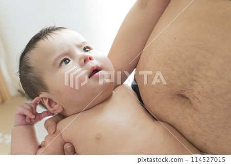 A woman's belly with stretch marks after giving birth and a smiling half-Japanese baby boy being held in his arms 114527015