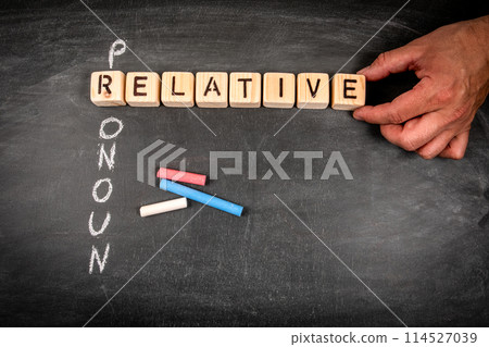 Relative pronoun. Wooden block crossword puzzle and pieces of chalk on a chalkboard background Relative pronoun. Wooden block crossword puzzle and pieces of chalk on a chalkboard background 114527039