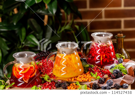 Set of three fruit teapots with lemon, orange, berries and apple at decorated in autumn style background. Set of three fruit teapots with lemon, orange, berries and apple at decorated in autumn style background. 114527438