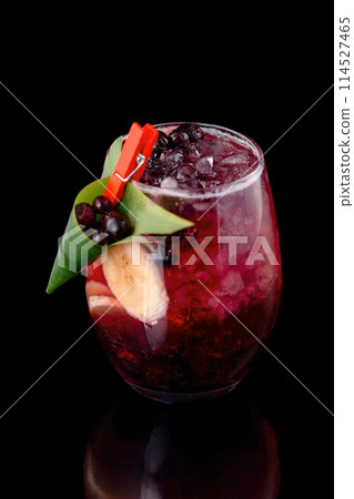 Glass of berries sangria with red wine, black currant, lemon and banana isolated at black background. Glass of berries sangria with red wine, black currant, lemon and banana isolated at black background. 114527465