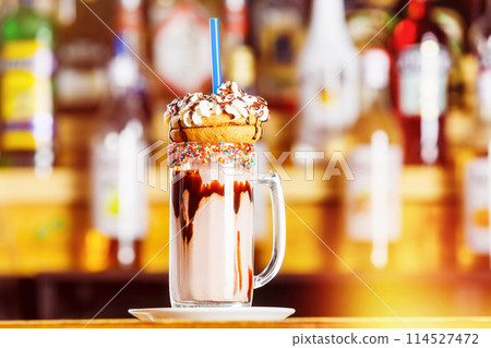 Closeup image of colorful coffee glass decorated with glaze and cookies at bar background. Closeup image of colorful coffee glass decorated with glaze and cookies at bar background. 114527472