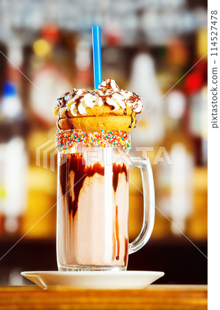Closeup image of colorful coffee glass decorated with glaze and cookies at bar background. 114527478