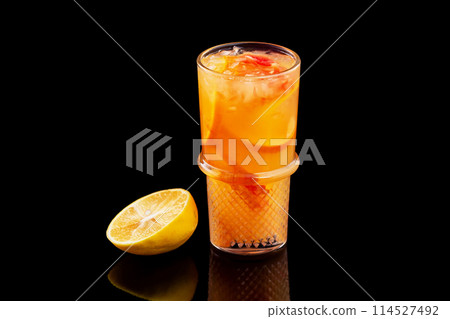 Closeup glass of fresh orange juice with ice isolated at black background. Closeup glass of fresh orange juice with ice isolated at black background. 114527492