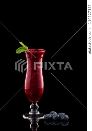 Glass of red currant berries fresh shake decorated with mint and blueberry isolated at black background. 114527525
