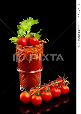 Glass of fresh red tomato juice decorated with celery and pepper isolated at black background. Glass of fresh red tomato juice decorated with celery and pepper isolated at black background. 114527625