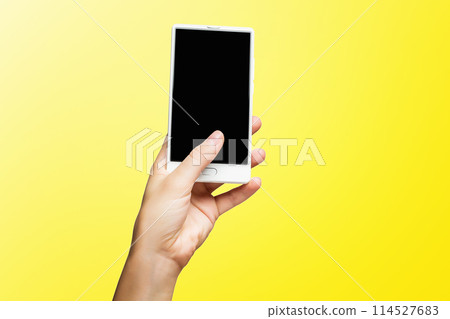 Mockup of female hand holding frameless cell phone with black screen isolated at yellow background. 114527683