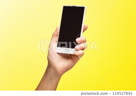 Mockup of female hand holding frameless cell phone with black screen isolated at yellow background. 114527691
