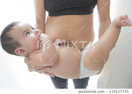 A woman's belly with stretch marks after giving birth and a smiling half-Japanese baby boy being held in his arms 114527735