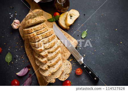 sliced bread on wooden cutting board on dark table 114527826