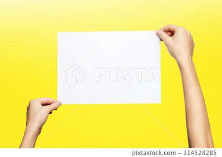 Mockup of female hands holding blank paper list isolated at yellow background. Mockup of female hands holding blank paper list isolated at yellow background. 114528285