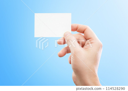 Male hand holding white business card at isolated blue background mockup. Male hand holding white business card at isolated blue background mockup. 114528290