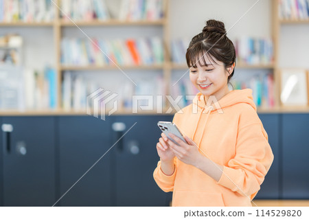 操作智慧型手機的大學生。 114529820