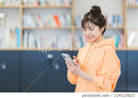 A university student operating a smartphone. A university student operating a smartphone. 114529825