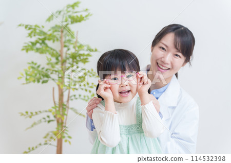 Ophthalmologist and amblyopic child wearing glasses 114532398