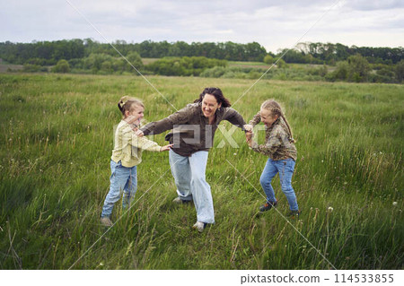 mother breaks up the children who are fighting in the rain in the field 114533855
