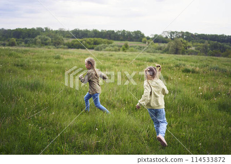girls play catch up in a field 114533872