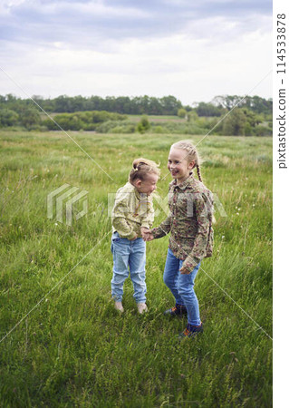 sisters hug and protect each other from the wind in the field 114533878