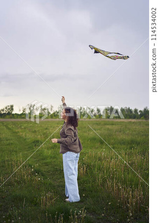 two little sisters and mother run and launch a kite in a field 114534002