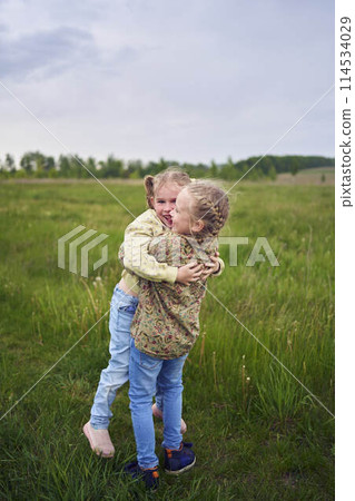 two sisters hug and kiss in the field two sisters hug and kiss in the field 114534029