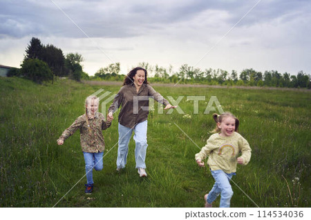 mother and children run holding hands in the field mother and children run holding hands in the field 114534036