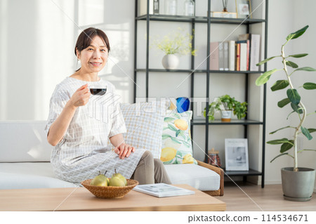 A middle woman relaxing in the living room. 114534671