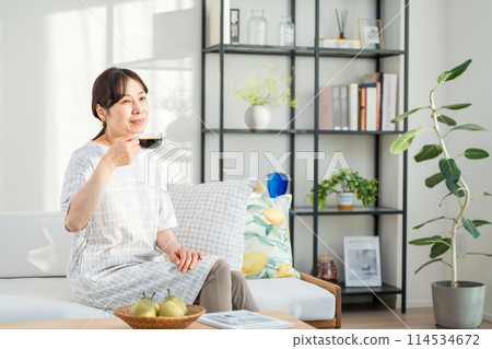 A middle woman relaxing in the living room. 114534672