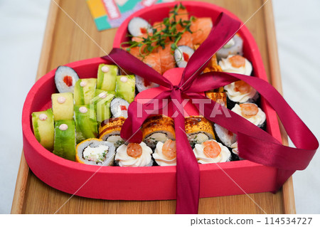 Heart shaped Valentine day sushi set. Classic sushi rolls, philadelphia, maki set for two, with two pairs of chopsticks for Valentine's dating dinner 114534727
