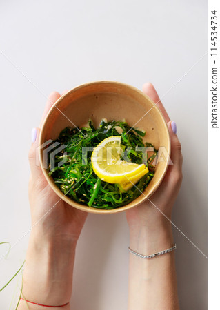 Hiyashi Wakame Salad In Kraft Food Delivery Container In Female Hands, Chuka Salad Hiyashi Wakame Salad In Kraft Food Delivery Container In Female Hands, Chuka Salad 114534734