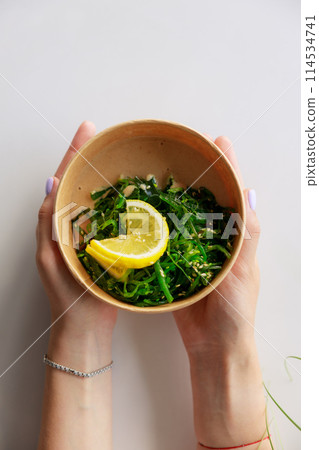 Hiyashi Wakame Salad In Kraft Food Delivery Container In Female Hands, Chuka Salad Hiyashi Wakame Salad In Kraft Food Delivery Container In Female Hands, Chuka Salad 114534741