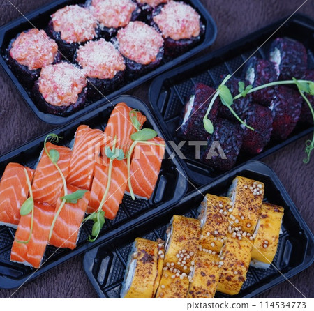 Sushi roll Philadelphia with salmon, smoked eel, avocado, cream cheese on black background. Sushi menu. Japanese food. Sushi roll Philadelphia with salmon, smoked eel, avocado, cream cheese on black background. Sushi menu. Japanese food. 114534773