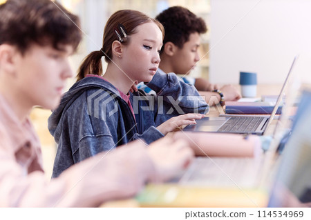 Portrait of Asian teenage girl using laptop in school in row with group of students copy space Portrait of Asian teenage girl using laptop in school in row with group of students copy space 114534969