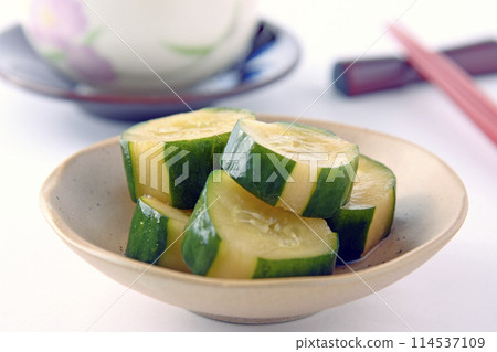 小盤子上的醃黃瓜,白色背景的茶杯裡放著筷子和筷子 小盤子上的醃黃瓜,白色背景的茶杯裡放著筷子和筷子 114537109