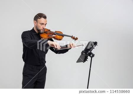 Handsome man holding a violin in his hands playing classic music 114538660