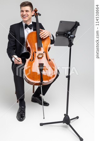 Young male musician performing with cello and music note 114538664
