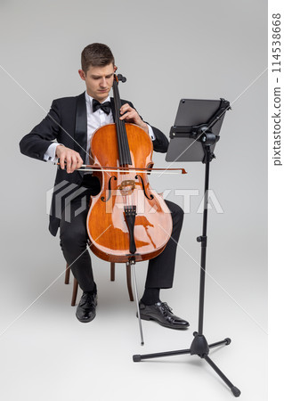 Man artist wearing tuxedo playing cello with music note 114538668