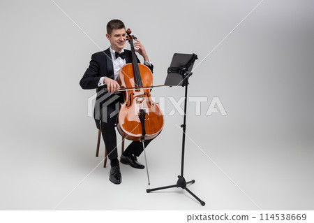 Man artist wearing tuxedo playing cello with music note 114538669
