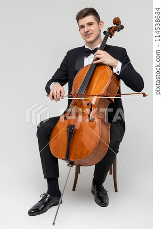 Musician sitting on chair playing cello Musician sitting on chair playing cello 114538684