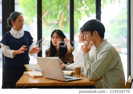 College students attentively listening to mature professor in the classroom 114538770