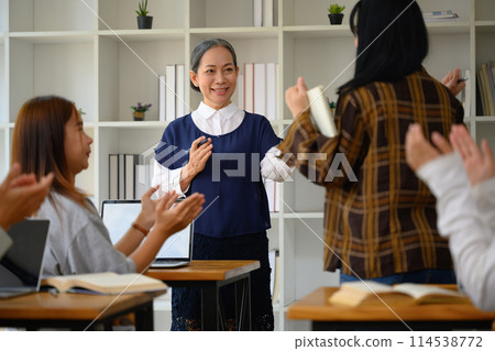 Group of college students and professor applauding to their classmate after giving presentation 114538772