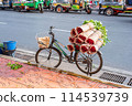 Bicycle loaded with bouquets of roses wrapped in paper with blurred tuk-tuks in the background. Flower market Pak Khlong Talat in Bangkok, Thailand 114539739