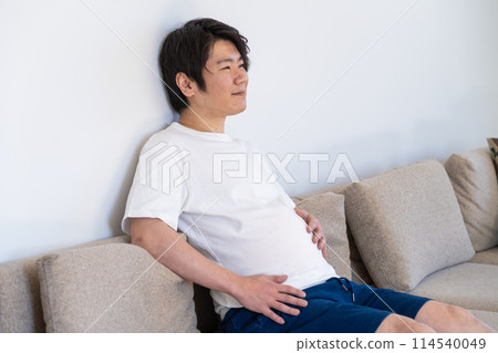 A man stroking his stomach after eating too much 114540049
