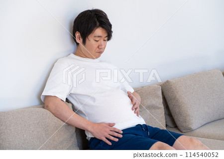 A man who is depressed when he sees his overeaten stomach 114540052