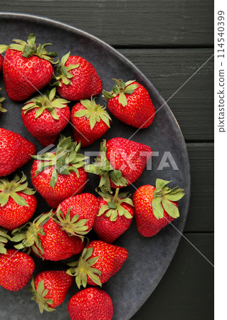 Top of view fresh strawberry in dark plate on black wooden background. Vertical photo 114540399